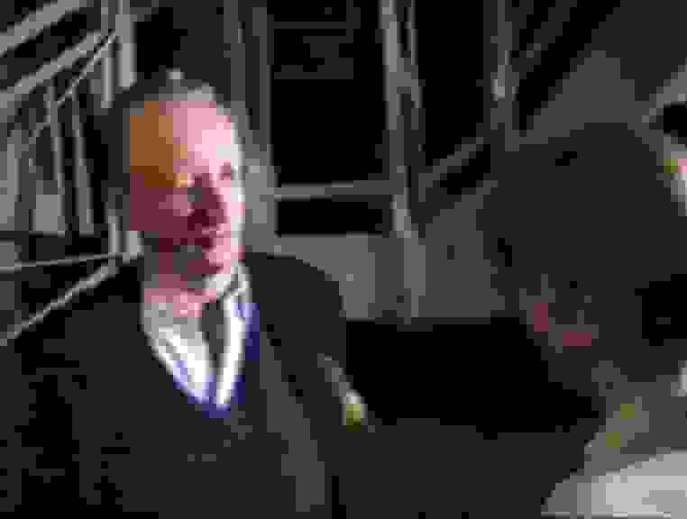 Interview mit Klaus Staeck am 1. Mai 1990, im Hintergrund Besucher und Besucherinnen im Hafthaus. Kamera: Rolf Staeck. Screenshot, Film zur Ausstellungseröffnung