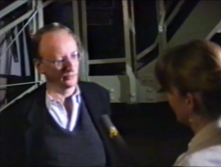 Interview mit Klaus Staeck am 1. Mai 1990, im Hintergrund Besucher und Besucherinnen im Hafthaus. Kamera: Rolf Staeck. Screenshot, Film zur Ausstellungseröffnung